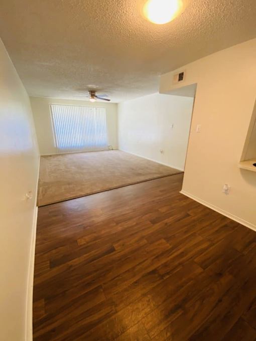 A room with wooden floors and a window with blinds.