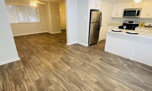 A kitchen with a refrigerator, microwave, and oven.