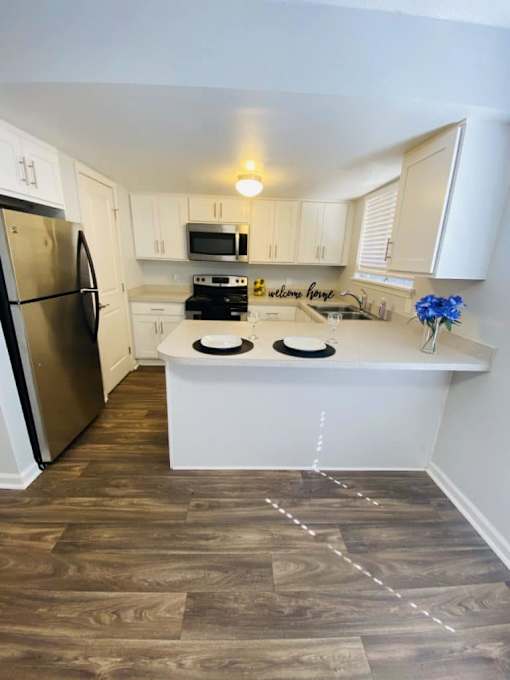 A kitchen with a refrigerator, microwave, oven, and sink.