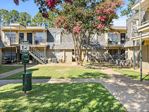 A sunny day at a residential complex with a green lawn and apartment buildings.