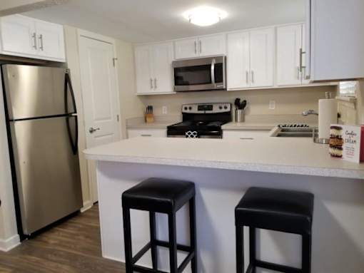 A kitchen with white cabinets and a stainless steel refrigerator.