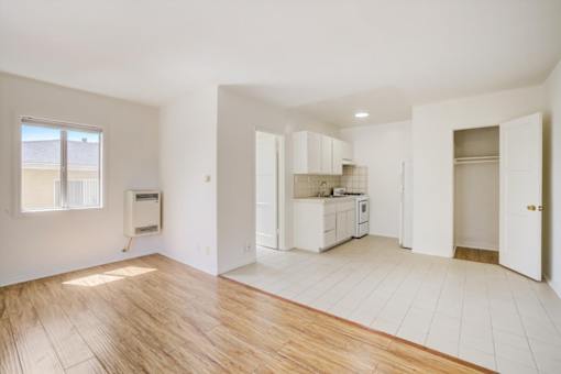 A spacious kitchen with white cabinets and a wooden floor.