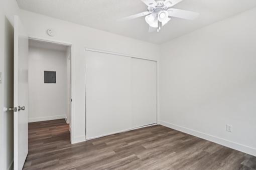 A room with a ceiling fan and wooden flooring.