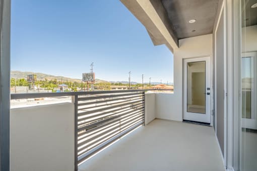 A balcony with a metal railing and a door leading to the outside.