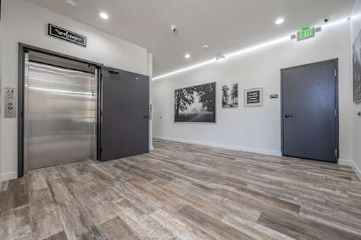 A hallway with a green exit sign and a stainless steel door on the left.