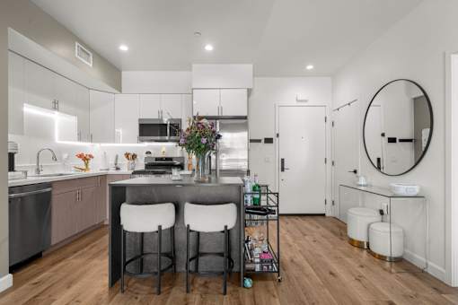 A modern kitchen with a bar stool and a round mirror.