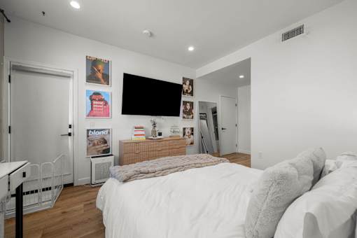 A bedroom with a large bed and a flat screen TV mounted on the wall.