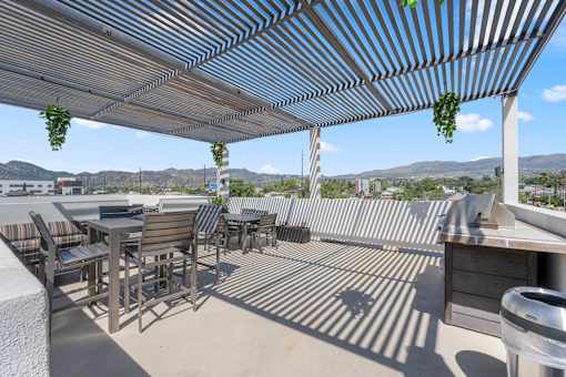 A patio with a striped awning and a table and chairs.