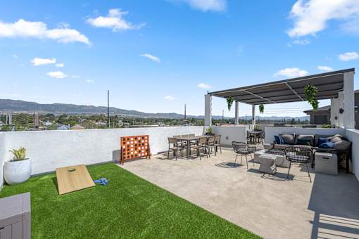 A patio with a white wall and a white pergola.