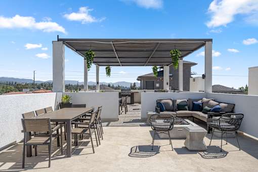 A patio with a table and chairs under a roof.