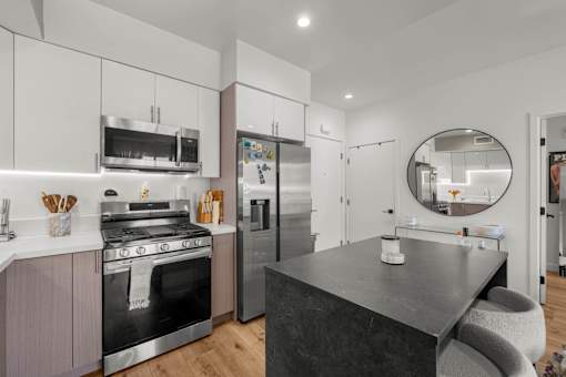 A modern kitchen with a black countertop and stainless steel appliances.