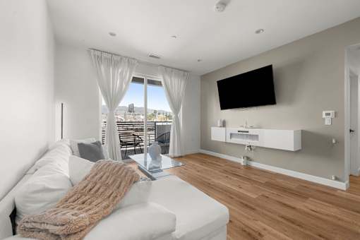 A modern living room with a white couch and a flat screen TV mounted on the wall.