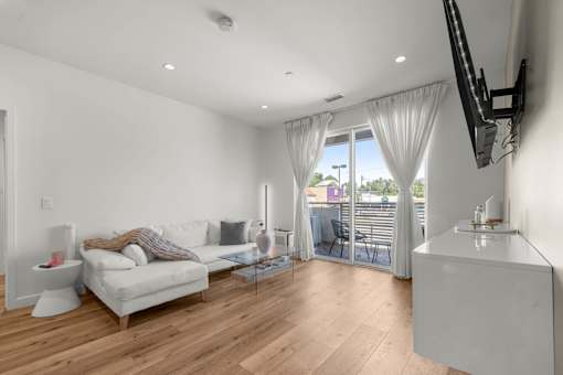 A living room with a white couch and a television on the wall.