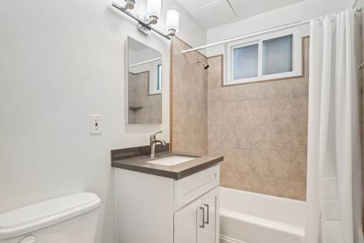 A bathroom with a white tub, sink, and shower.