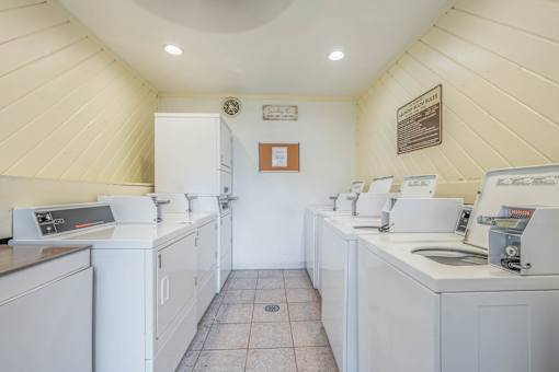 A laundromat with washers and dryers is clean and empty.