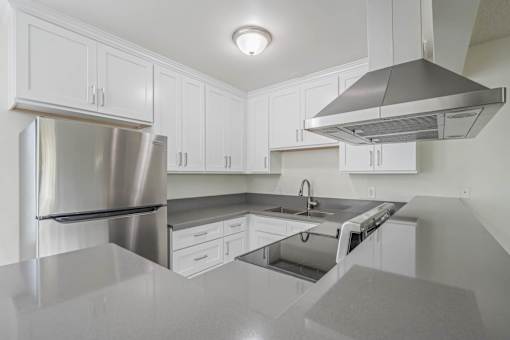 A modern kitchen with a stainless steel refrigerator and a range hood.
