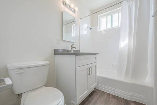 A white bathroom with a toilet, sink, and mirror.