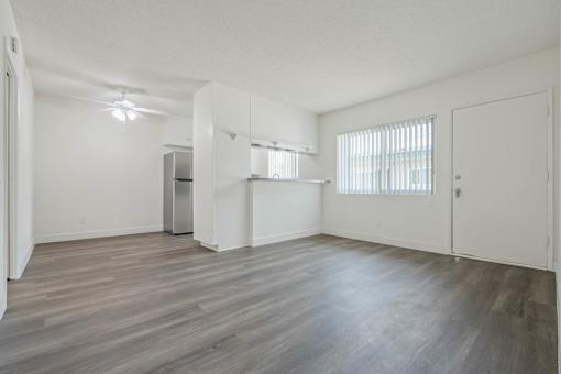 A spacious room with wooden flooring and white walls.