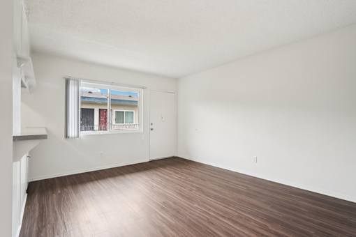 A room with a window and wooden flooring.