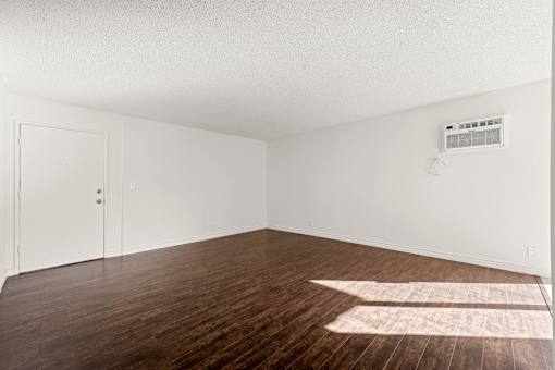 A room with a wooden floor and a white ceiling with a vent.