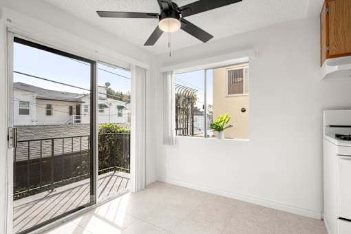 A room with a ceiling fan and sliding glass doors leading to a balcony.