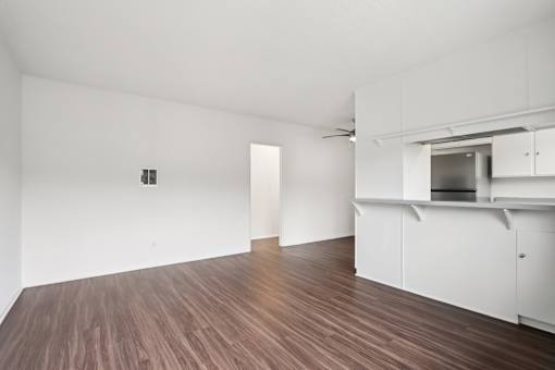 A room with white walls and wooden flooring with a white cabinet and a white door.