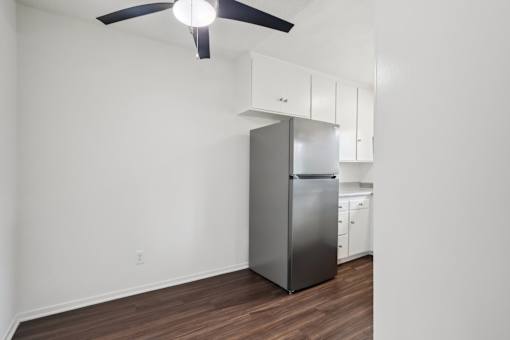 A kitchen with a stainless steel refrigerator and white cabinets.