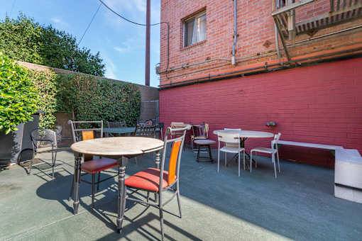 A patio with a table and chairs is surrounded by a red wall.