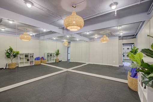 A room with grey flooring and white walls, containing a white cabinet, a plant, and a basket.