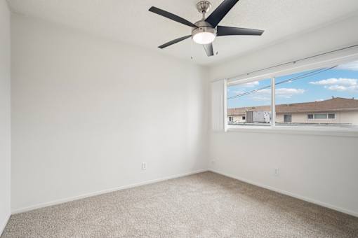 A room with a ceiling fan and carpeted floor.