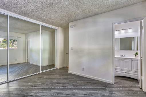 an empty living room with a mirror and a bathroom