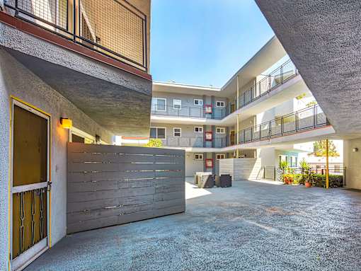 the entrance to an apartment building with a driveway and a wooden door