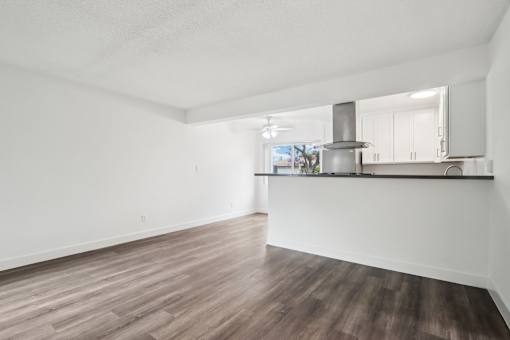 A spacious room with wooden flooring and white walls.