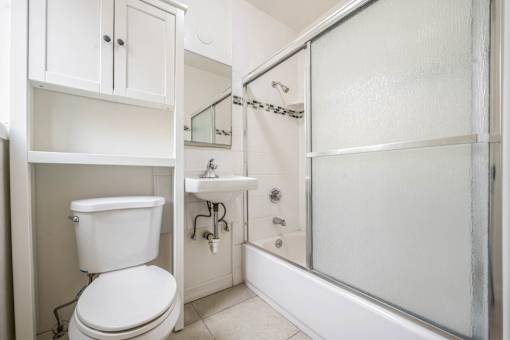 A white toilet is in a bathroom with a glass shower door.