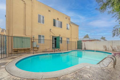 A small pool in front of a tan building.
