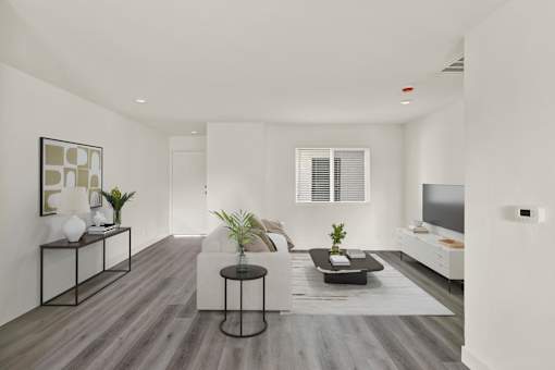 A modern living room with a white couch, a black coffee table, and a TV on the wall.