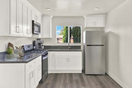 A modern kitchen with white cabinets and a stainless steel refrigerator.