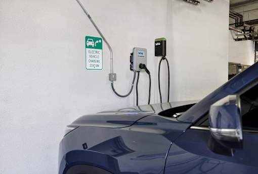 A blue car is plugged into an electric vehicle charging station.