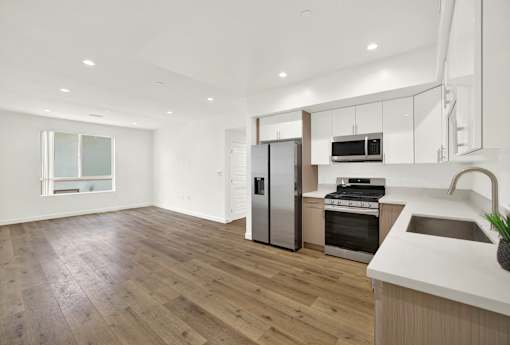 A modern kitchen with wooden floors and stainless steel appliances.