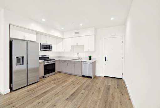 A modern kitchen with wooden floors and white walls.