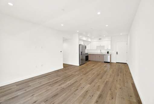 A spacious room with wooden flooring and white walls.