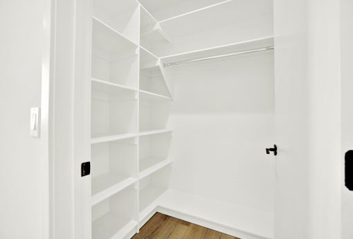 A white shelving unit in a room with a light switch on the wall.
