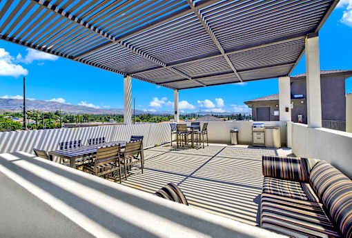 A patio with a striped couch and a striped umbrella.