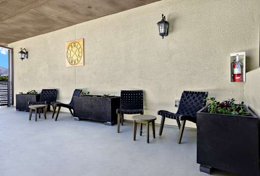 A row of black chairs with wooden legs are lined up against a wall.