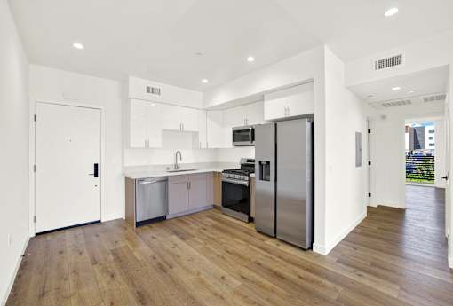 A modern kitchen with wooden floors and stainless steel appliances.
