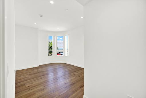 A white room with a wooden floor and pictures on the wall.