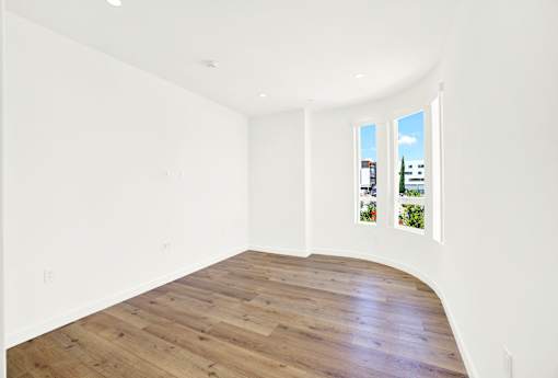 A room with wooden flooring and white walls.