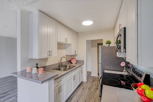 A modern kitchen with white cabinets and a stainless steel stove.