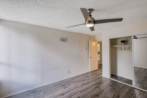 A room with a ceiling fan and a closet with shelves.