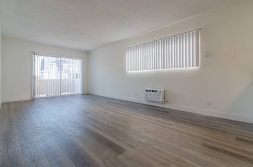 A room with wooden floors and a window with blinds.